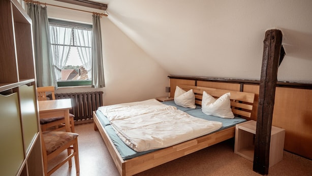 Quarto com cama de madeira, escrivaninha e cadeira.