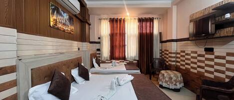 A hotel room with two beds, a ceiling fan, a TV, and a checkered wall pattern.