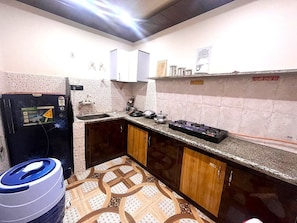Cocina compacta con refrigerador, pileta y electrodomésticos en la encimera.