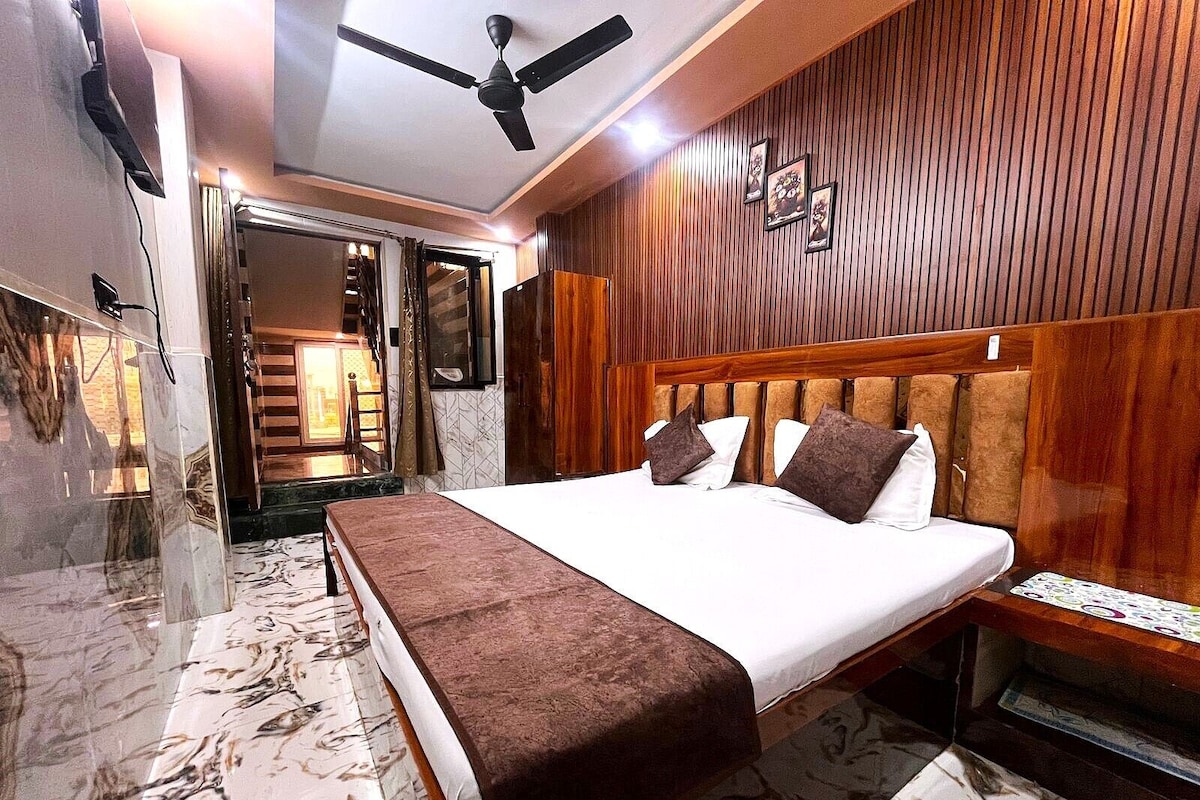 A hotel room with a bed, a ceiling fan, wooden paneling, and a marble floor.