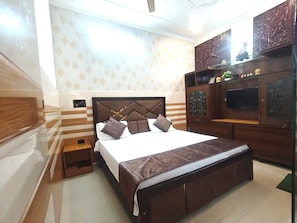 Un dormitorio con una cama grande, cabecero de madera y televisor montado en la pared.