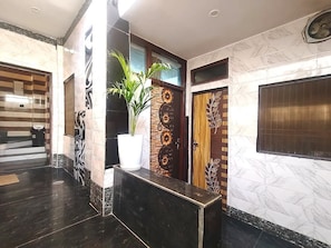 A reception area with a marble floor, a reception desk, a potted plant, and decorative panels. - VATS VILLA  (Vrindavan)