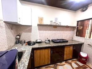 A kitchen with granite countertops, wooden cabinets, and a gas stove. - VATS VILLA  (Vrindavan)