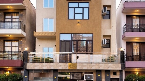 Un edificio residenziale a più piani con un ingresso centrale, balconi e piante in vaso.