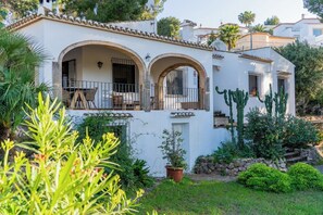 A white building with a patio, a cactus, and a garden. - Vrbo Property (VC)