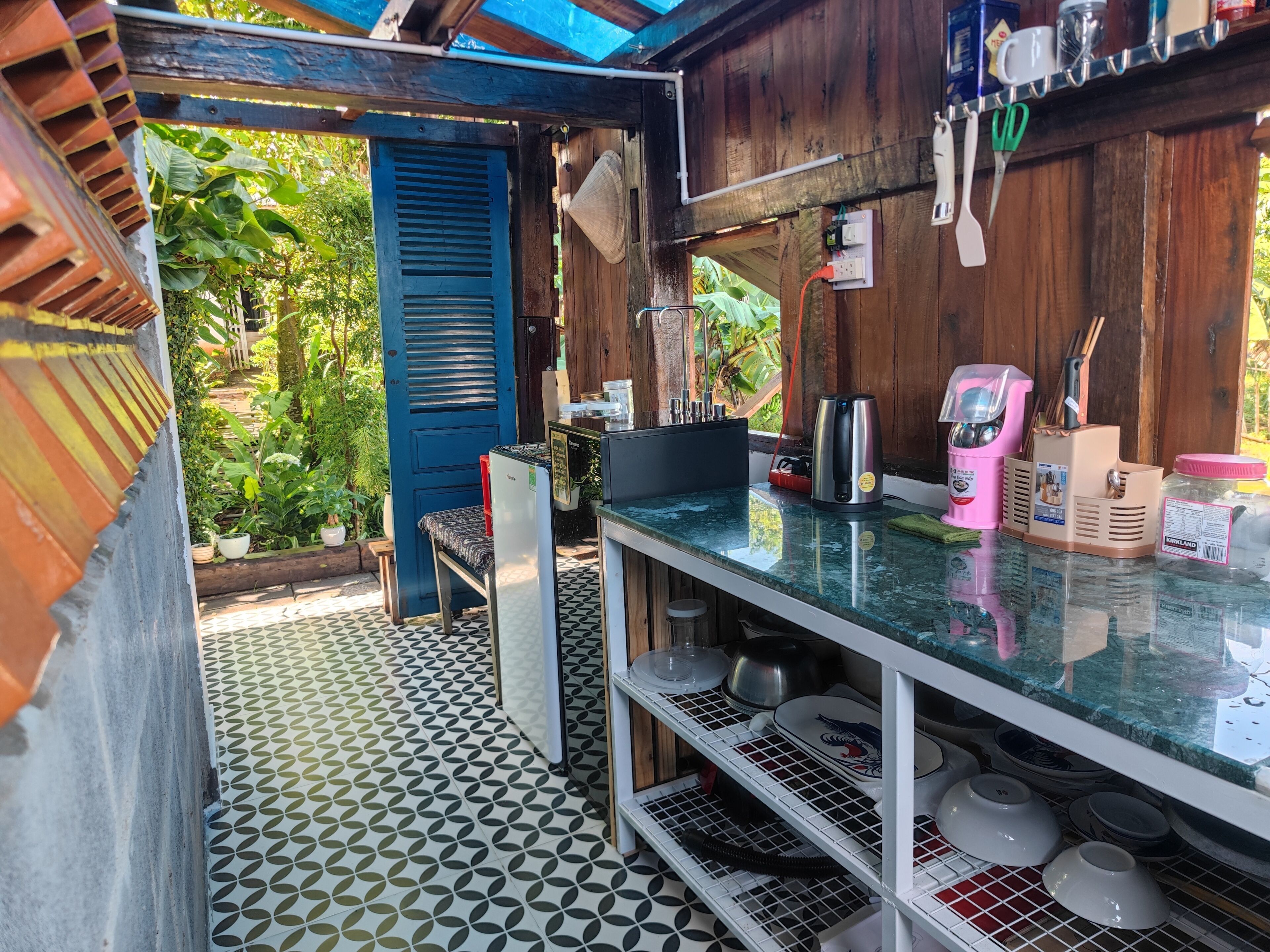 A kitchen with a blue door, a countertop with various appliances, and a patterned floor.