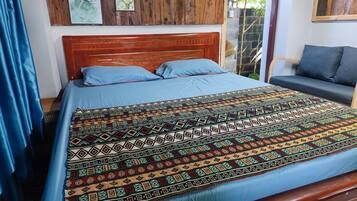 A bed with a patterned bedspread, a wooden headboard, and a blue pillow.