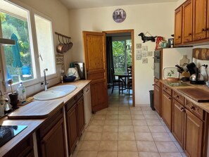 Una cocina con armarios de madera, un fregadero, una estufa y un comedor visible a través de una puerta abierta.