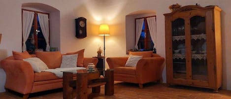 A cozy living room with two sofas, a wooden coffee table, a lamp, a clock, and a cabinet.