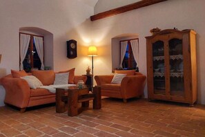 A cozy living room with two sofas, a wooden coffee table, a lamp, a clock, and a cabinet.