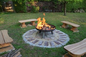 A circular fire pit with benches around it in a grassy outdoor area. - Moarhofstöckl "Country Romance for Two" (Landscha bei Weiz)