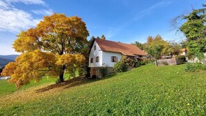 Una casa blanca amb teulada vermella, envoltada d'una zona verda i arbres amb fulles de tardor.
