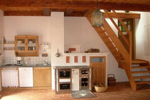 Une cuisine rustique avec des meubles en bois, un four encastré et un escalier en bois.