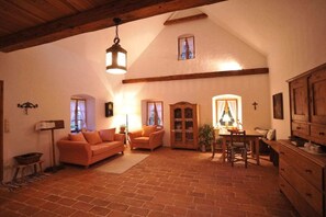 A cozy living room with a fireplace, a dining table, and a sofa. - Moarhofstöckl "Country Romance for Two" (Landscha bei Weiz)