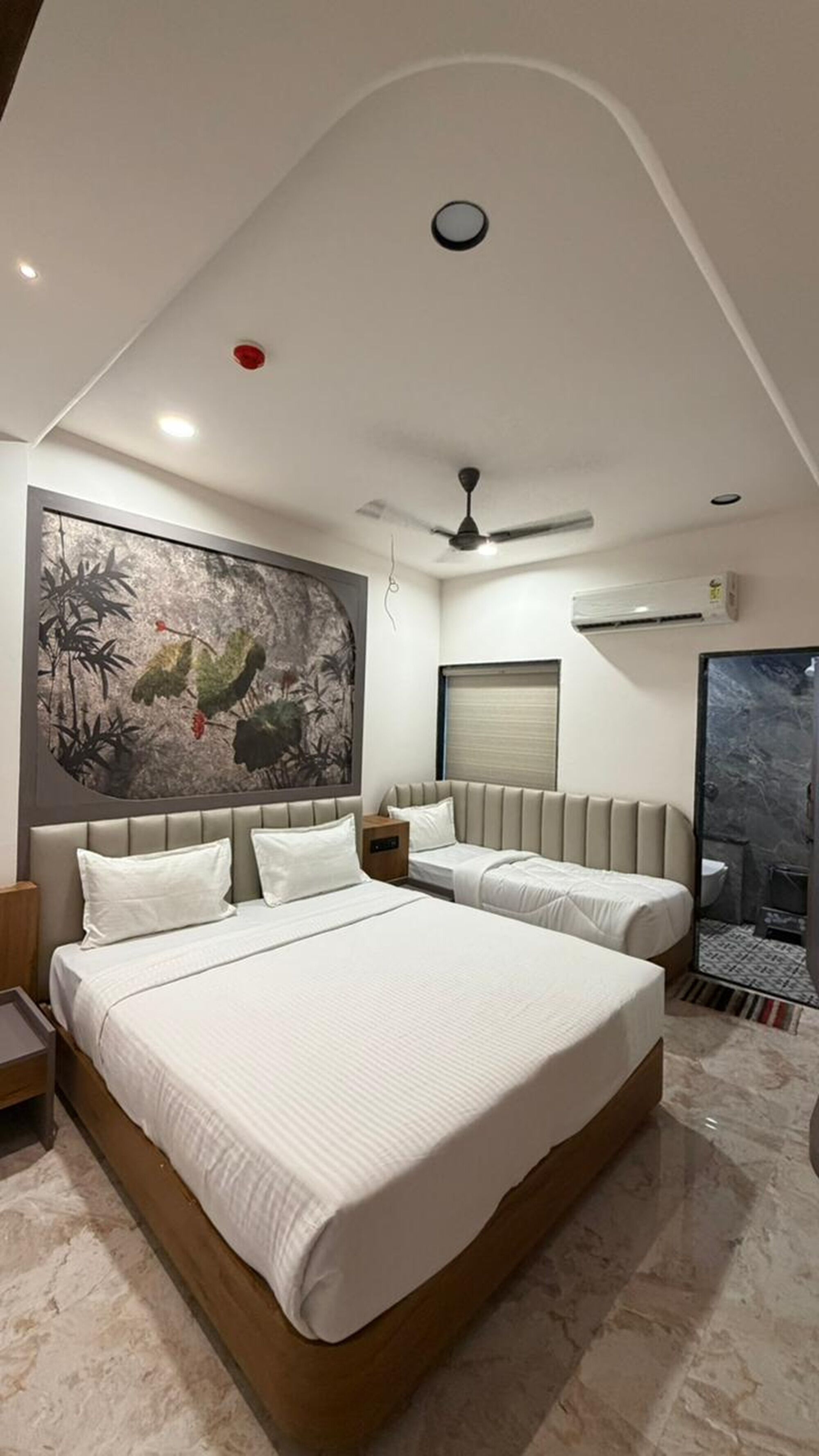 Un dormitorio moderno con una cama grande, un ventilador de techo y un equipo de aire acondicionado instalado en la pared.