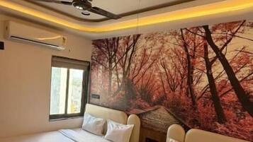 Quarto de hotel com duas camas, um ventilador de teto, uma janela e um mural na parede.