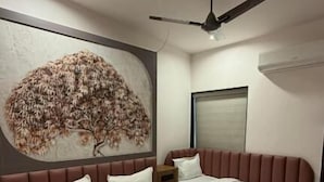 A bedroom with a large bed, a smaller bed, a ceiling fan, and a wall-mounted air conditioner. - Hotel Ishant (Dwarka)