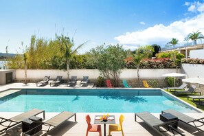 A rectangular swimming pool with lounge chairs and a table, surrounded by vegetation and a clear sky. - LES ROCHES BLANCHES (Porto-Vecchio)