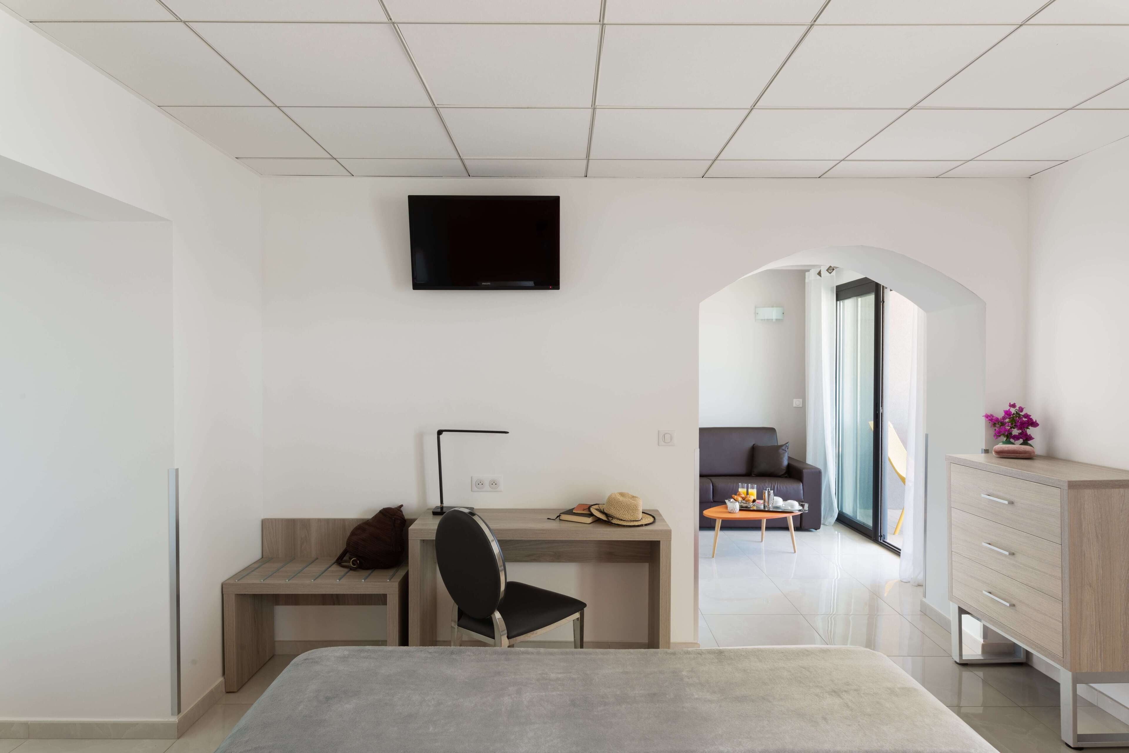 Een moderne hotelkamer met een bed, bureau, stoel, televisie en uitzicht op de zithoek.