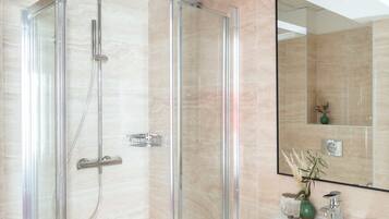 Een moderne badkamer met een douchecabine van glas, een witte wastafel en een spiegel.