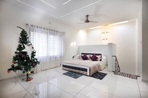 A modern bedroom with a bed, a Christmas tree, and a ceiling fan.