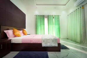 A modern bedroom with a bed, curtains, and a nightstand. - Alleppey Breeze by 8MH - Luxury Backwater Villa (Mararikulam)