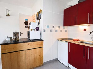 A compact kitchen with a microwave, a coffee machine, and a sink. - A Stopover at Juno - Balcony 100 meters from the beach (Courseulles-sur-Mer)