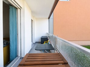 A balcony with a wooden bench, a small table, and a chair. - A Stopover at Juno - Balcony 100 meters from the beach (Courseulles-sur-Mer)