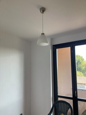 A room with a ceiling light fixture, a door leading outside, and a chair. - Breakfast and Beverages (Biella)