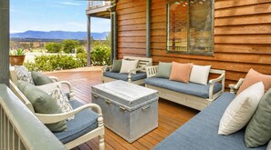 A wooden deck with outdoor furniture, including a sofa and chairs, and a vintage-style trunk.