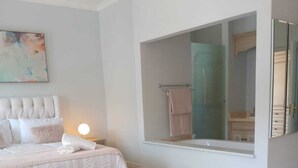 Ett sovrum med en säng, ett sängbord, en lampa, en stor spegel och en mönstrad matta.