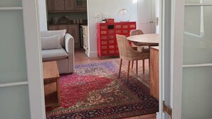 Ein Zimmer mit Essbereich, einer Couch, einem roten Stauraum und einer Küche im Hintergrund.