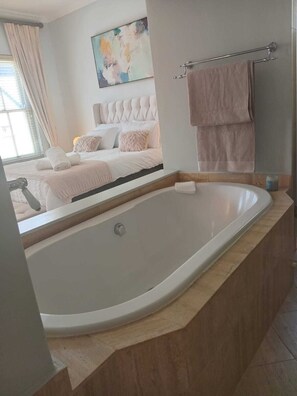 Een moderne badkamer met een ruime badkuip, een douchegedeelte en een bed met hoofdeinde.