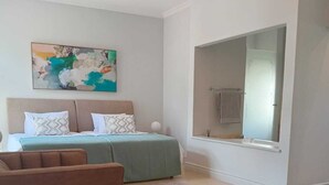 Ein Schlafzimmer mit einem Bett, einem Sessel, einem Teppich, einem Gemälde und einem großen Spiegel.