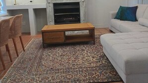 Ett vardagsrum med en öppen spis, en soffa, ett soffbord och två tavlor på väggen.