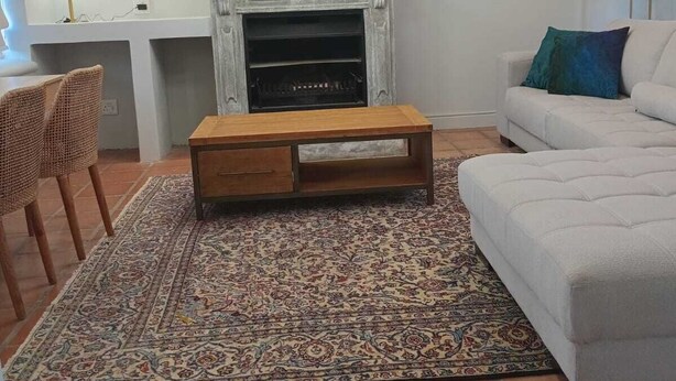 Ein Wohnzimmer mit Kamin, einer Couch, einem Couchtisch und zwei Bildern an der Wand.