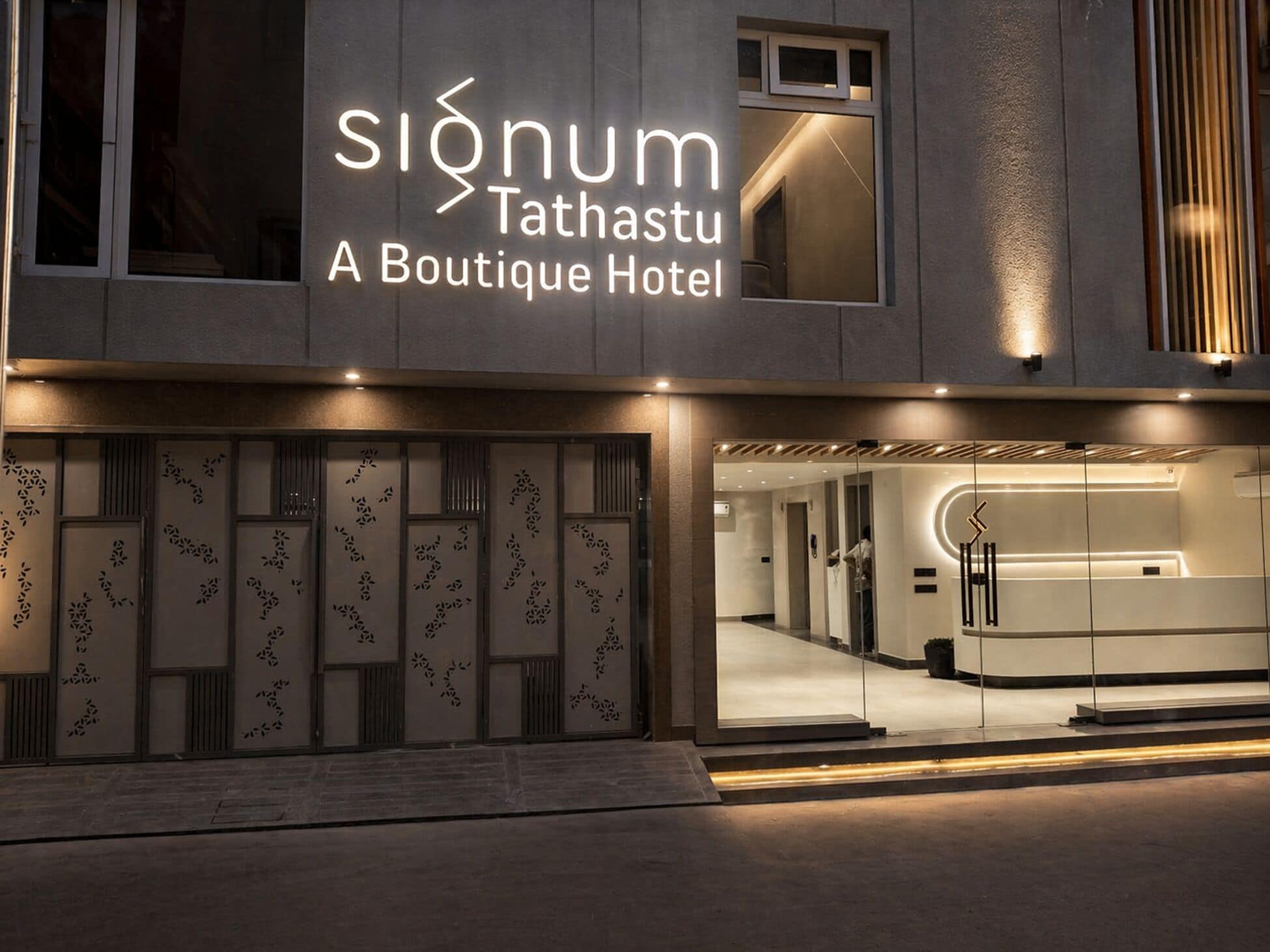 A modern hotel entrance with a sign reading 'SIŌNUM Tathastu A Boutique Hotel.'