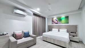 A modern hotel room with a bed, a sofa, an air conditioning unit, a flat-screen TV, and a ceiling fan. - Signum Tathastu Boutique Hotel- Haridwar (Haridwar)