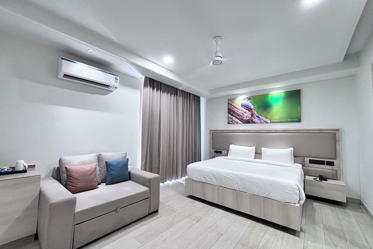 Ein modernes Hotelzimmer mit einem Bett, einer Couch, einer Klimaanlage, einem Flachbildfernseher und einem Deckenventilator.
