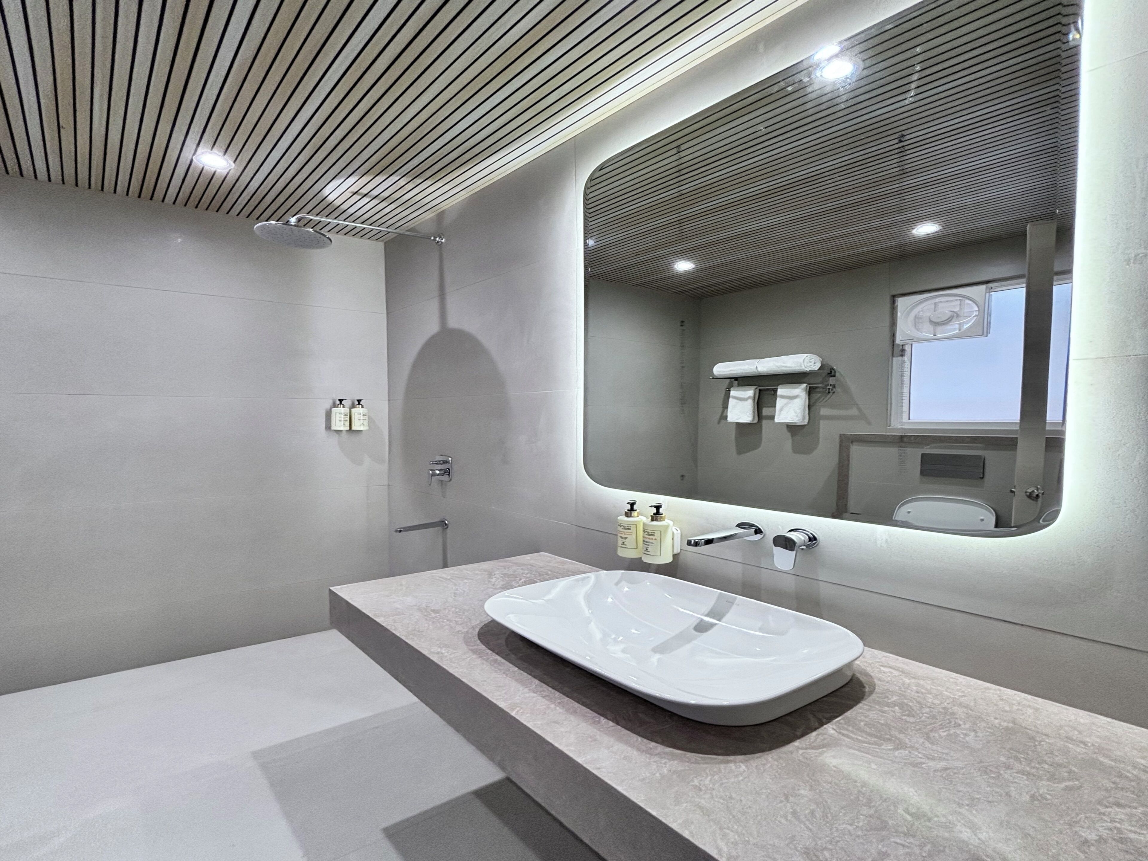 Une salle de bain moderne avec un grand miroir, une baignoire et une douche.