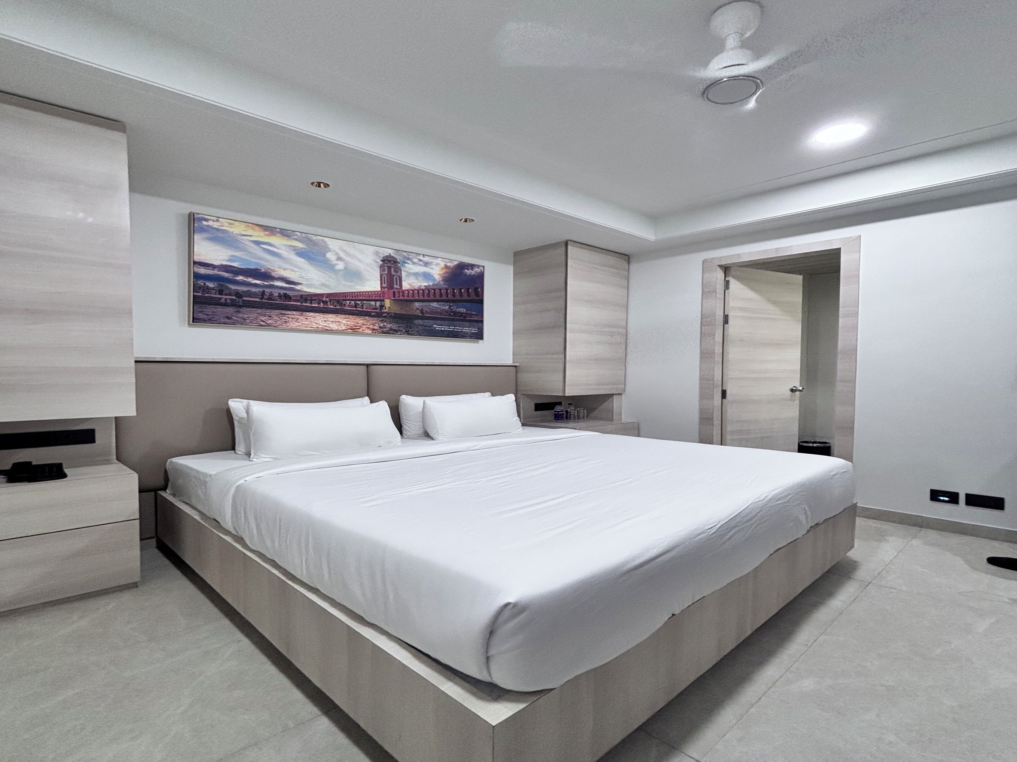 Un dormitorio moderno con una cama grande, una mesita de noche, un armario y un cuadro en la pared.
