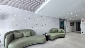 A modern interior with two green sofas, a small table, and a wall with bird decals. - Signum Tathastu Boutique Hotel- Haridwar (Haridwar)