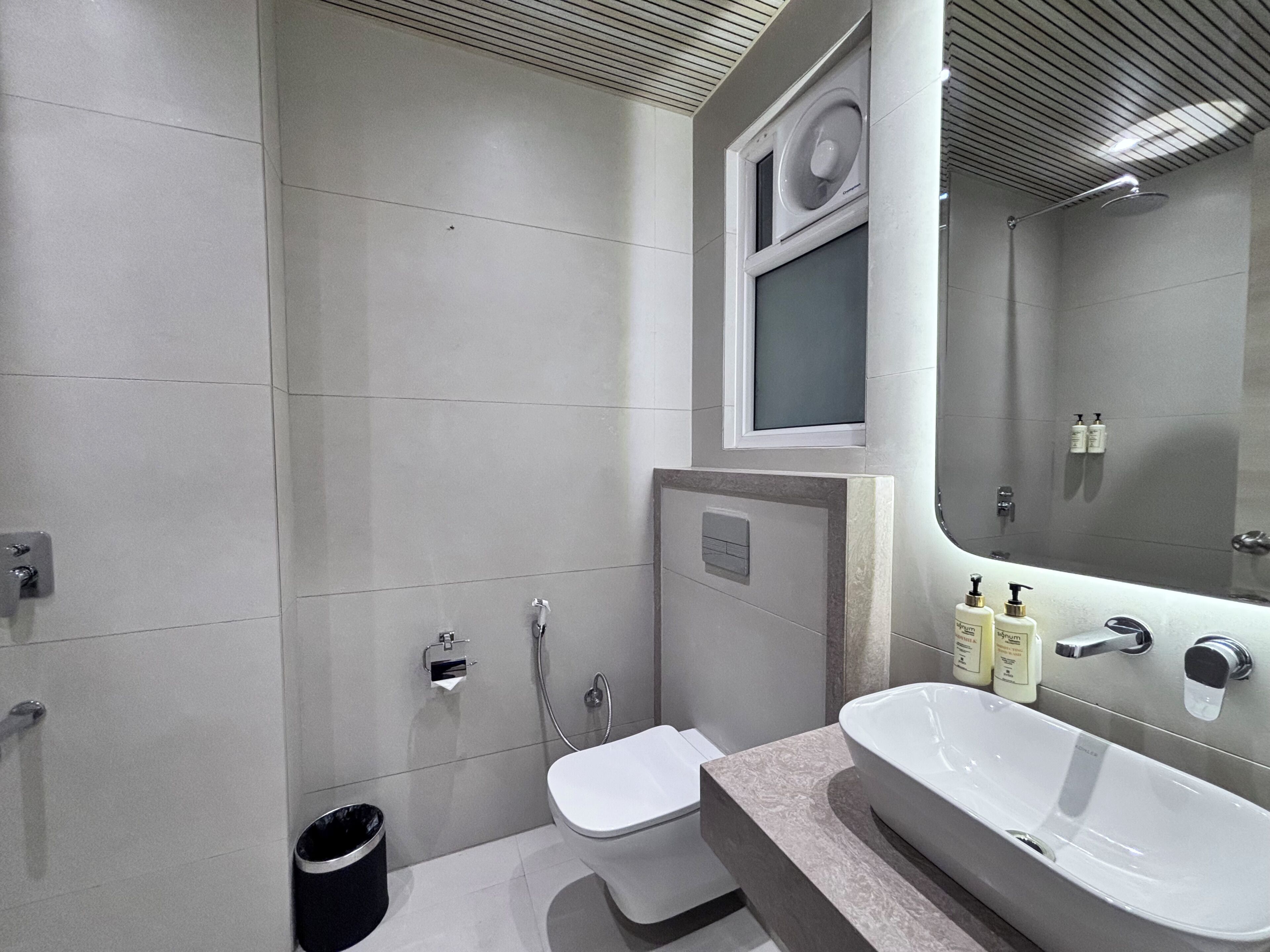 Ein modernes Badezimmer mit Toilette, Bidet und einem großen Waschbecken mit Spiegel darüber.
