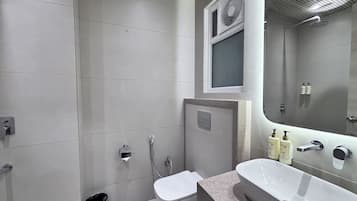 A modern bathroom with a toilet, bidet, and a large sink with a mirror above.