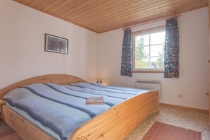 A bedroom with a wooden bed, a window with curtains, a radiator, and a framed picture on the wall. - Swedish House Red Water Lily (Userin)