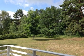 A grassy area with a white fence and trees in the background. - Swedish House Red Water Lily (Userin)