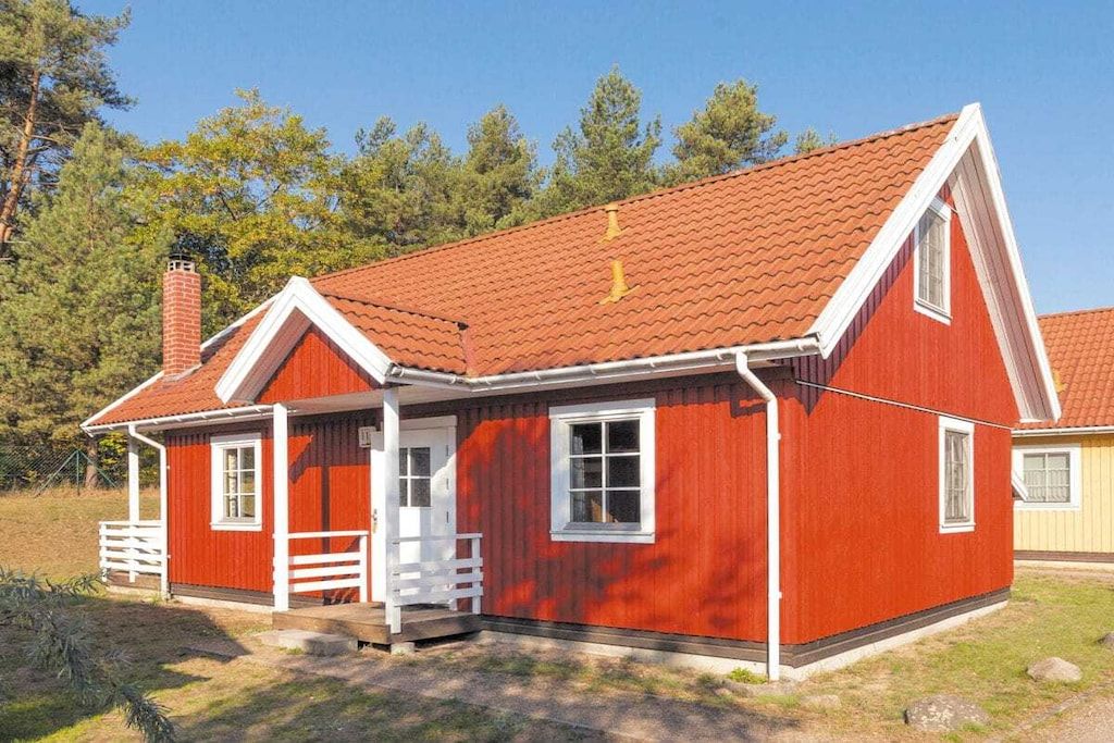 Ett rött trähus med en vit veranda och en skorsten.