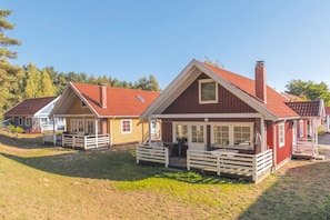 A row of red and yellow cabins with white railings, each with a porch and outdoor seating area. - Swedish House Red Water Lily (Userin)