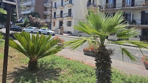 A residential area with multi-story buildings, a street with parked cars, and palm trees. - Vrbo Property (Pozzuoli)