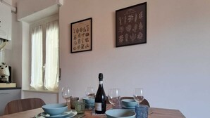 A dining area with a long table set for four, featuring blue plates and a bottle of wine. - Vrbo Property (Pozzuoli)